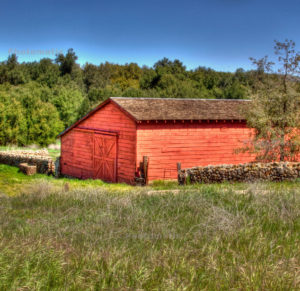 An old red barn and stone wall in a rural setting represents property types that often require evaluation under the California Environmental Quality Act (CEQA).